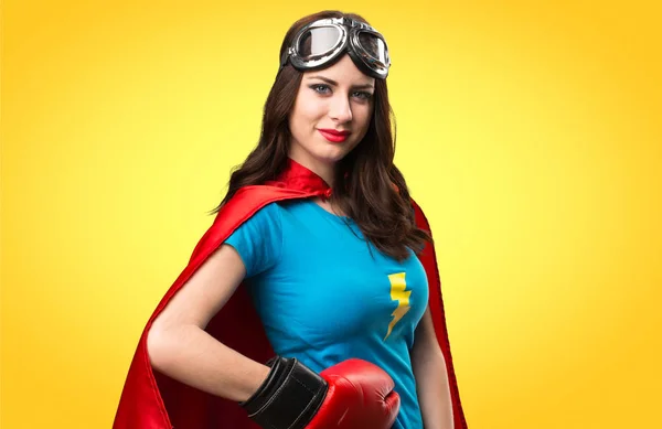 Pretty superhero girl  with boxing gloves on colorful background