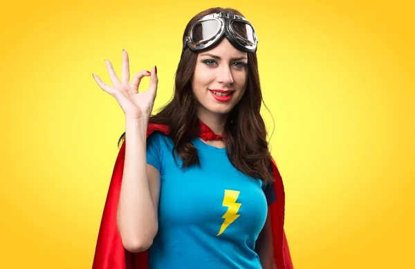 Menina super-herói bonito fazendo OK sinal no fundo colorido — Fotografia de Stock