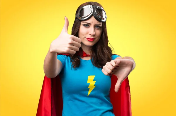 Dívka hezká superhrdina dělat dobré špatné znamení na barevné poza — Stock fotografie