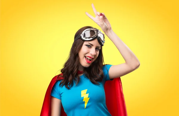 Hezká superhrdina dívka dělat vítězství gesto na barevné backgro — Stock fotografie