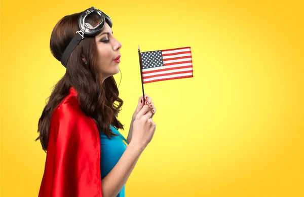 Dívka hezká superhrdina držení americkou vlajku na barevné pozadí — Stock fotografie