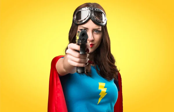 Pretty superhero girl holding a pistol on colorful background