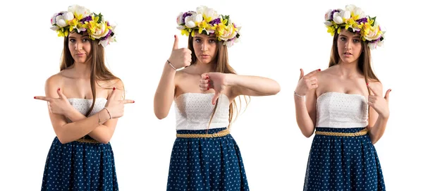 Girl with crown of flowers making good-bad sign — Stock Photo, Image