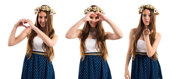 Menina com coroa de flores fazendo um coração com as mãos — Fotografia de Stock
