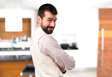 Yakışıklı adam kollarını ile yelek ile evin içinde geçti