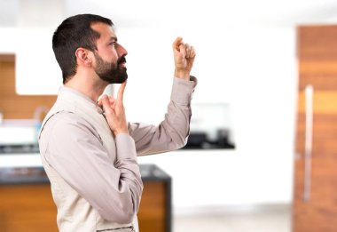 Evin içinde küçük işareti yapma yelek ile yakışıklı adam