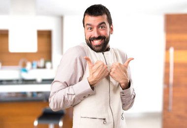 Başparmak ile yelek ile yakışıklı adam yukarı evin içinde