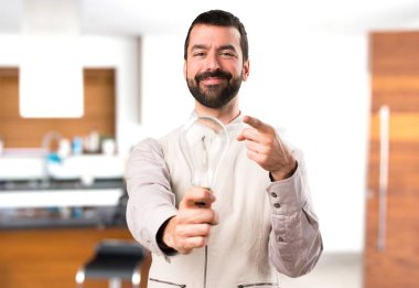 Bir ampul evin içinde tutarak yelek ile yakışıklı adam