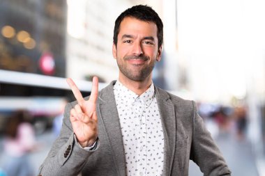 Yakışıklı adam iki odaklanmamış arka plan üzerinde sayma