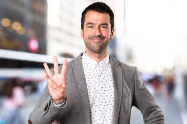 Yakışıklı adam üç odaklanmamış arka plan üzerinde sayma