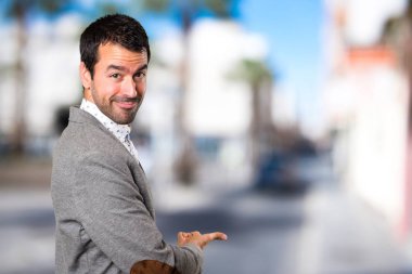 Yakışıklı adam bir şey odaklanmamış arka plan üzerinde sunulması