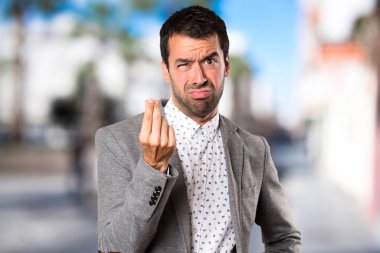 Yakışıklı adam yapma para jest odaklanmamış arka plan üzerinde