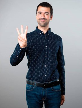 Yakışıklı adam üç gri arka plan üzerinde sayma