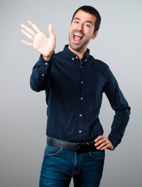 Yakışıklı adam gri arka plan üzerinde selamlayan