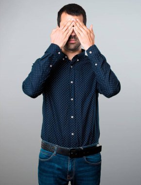 Yakışıklı adam gözlerini gri arka plan üzerine kaplama