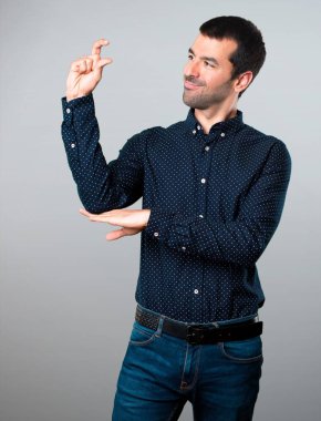 Yakışıklı adam küçük yapma gri arka plan üzerinde oturum