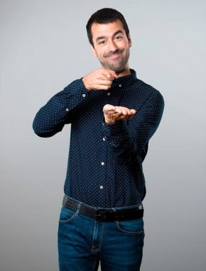 Yakışıklı adam bir şey gri arka plan üzerinde tutan