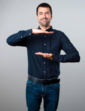 Yakışıklı adam bir şey gri arka plan üzerinde tutan