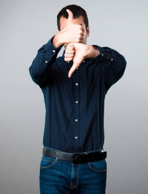 Yakışıklı adam iyi-kötü işareti gri arka plan üzerinde yapma