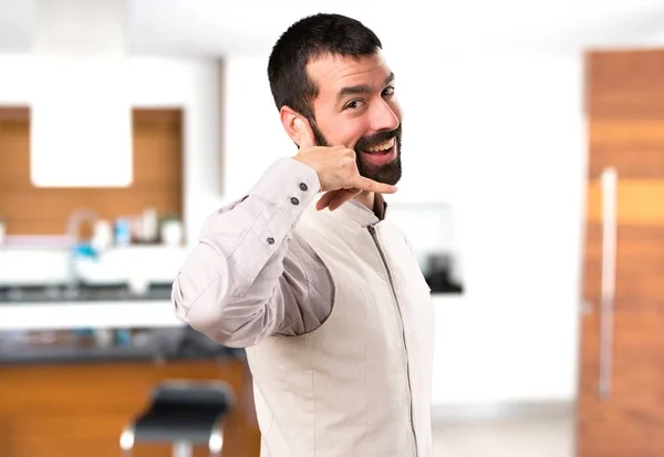 Bel homme avec gilet faisant geste de téléphone à l'intérieur de la maison — Photo