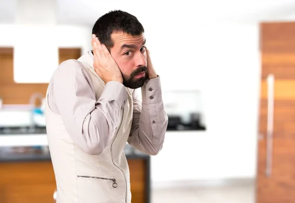 Schöner Mann mit Weste, die seine Ohren im Haus verdeckt — Stockfoto