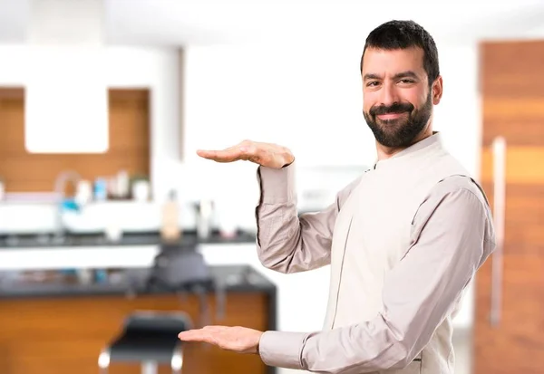 Bonito homem com colete segurando algo dentro da casa — Fotografia de Stock