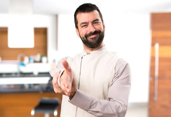 Bonito homem com colete fazendo um acordo dentro da casa — Fotografia de Stock