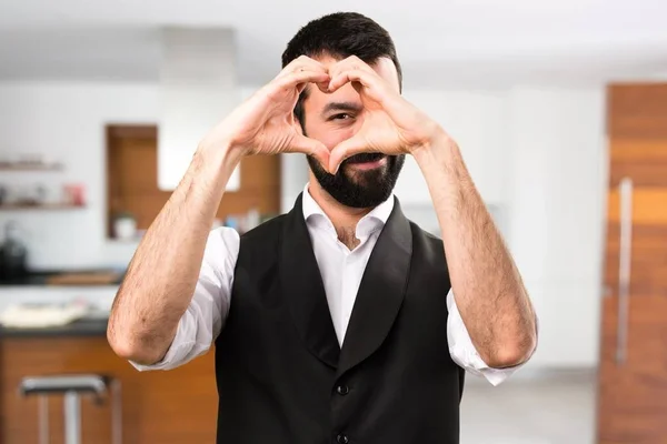 Cool man making a heart with his hands inside house