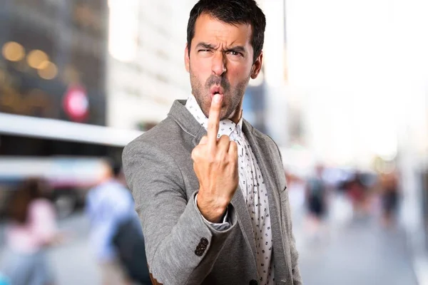 Bonito homem fazendo gesto chifre em fundo desfocado — Fotografia de Stock