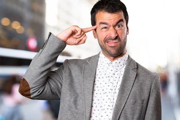 Hombre guapo haciendo un gesto loco en el fondo desenfocado — Foto de Stock