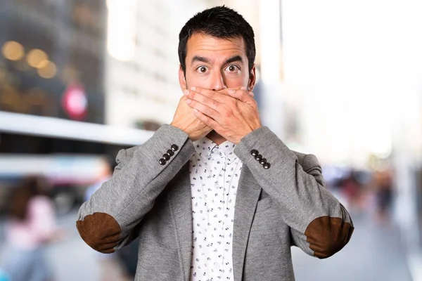 Handsome man covering his mouth on unfocused background — Stock Photo, Image
