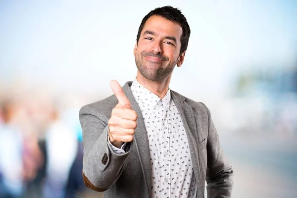 Handsome man with thumb up on unfocused background