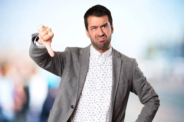 Hombre guapo haciendo mala señal en el fondo desenfocado — Foto de Stock