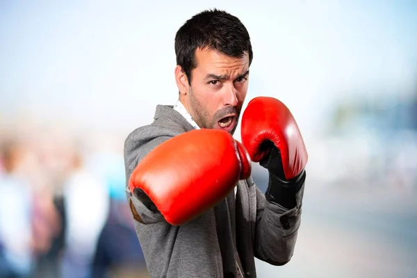 Hombre guapo con guantes de boxeo sobre fondo desenfocado — Foto de Stock