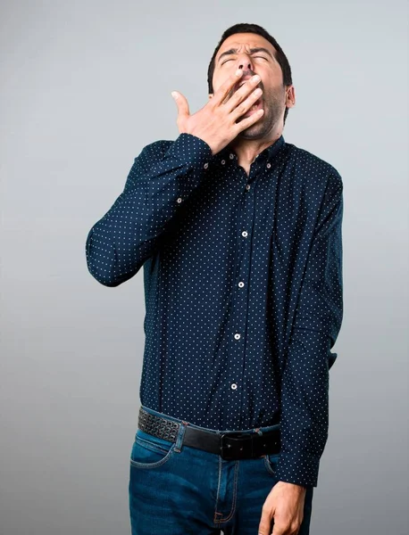 Hombre guapo bostezando sobre fondo gris — Foto de Stock