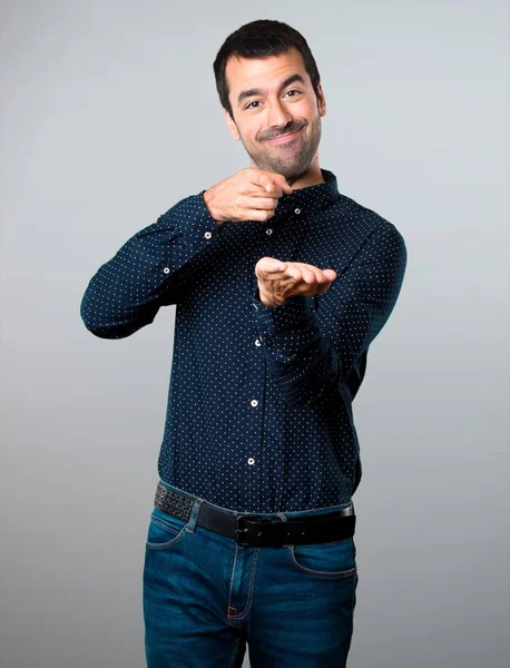 Yakışıklı adam bir şey gri arka plan üzerinde tutan