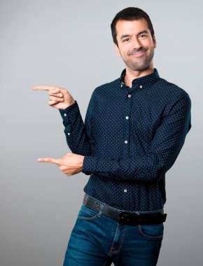 Yakışıklı adam lateral gri arka plan üzerine işaret