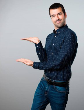 Yakışıklı adam bir şey gri arka plan üzerinde sunulması