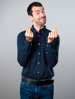 Yakışıklı adam yapma para jest gri arka plan üzerinde