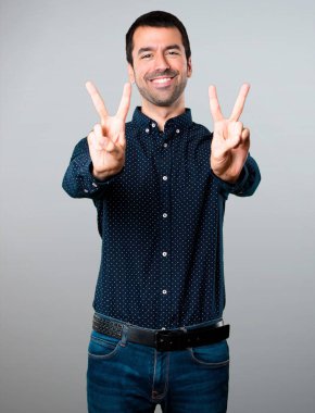 Yakışıklı adam yapma zafer jest gri arka plan üzerinde