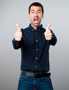 Gri arka plan üzerinde başparmak ile yakışıklı adam