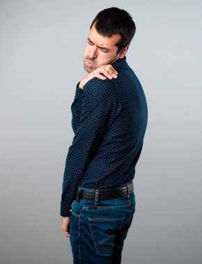 Gri arka plan üzerinde omuz ağrısı ile yakışıklı adam