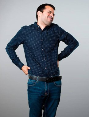 Gri arka plan üzerinde sırt ağrısı olan yakışıklı adam