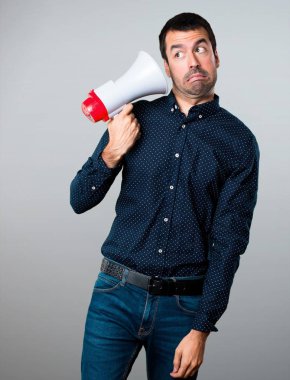 Yakışıklı adam bir megafon gri arka plan üzerinde tutan