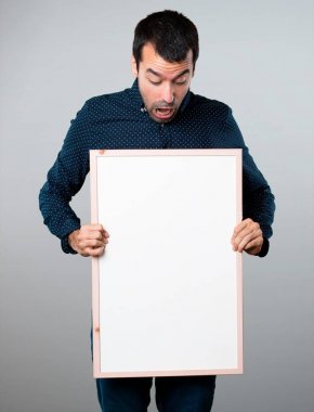Yakışıklı adam gri arka plan üzerinde boş bir afişini holding