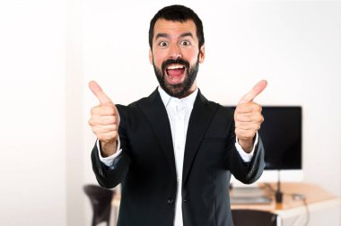 Ofiste başparmak ile yakışıklı işadamı