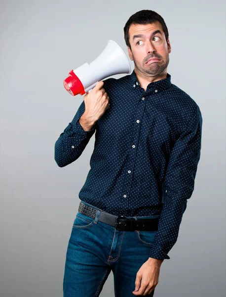 Yakışıklı adam bir megafon gri arka plan üzerinde tutan