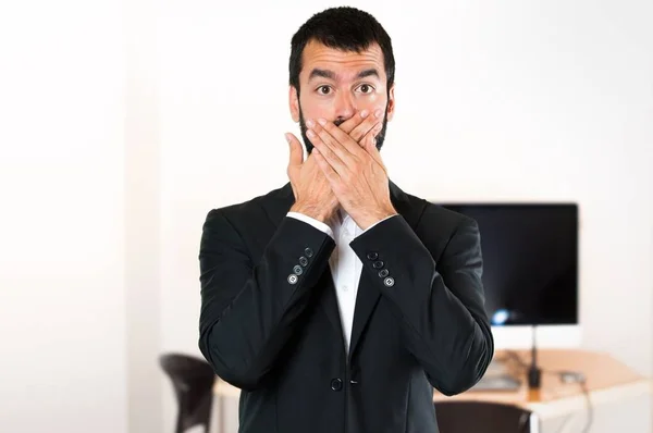 Hombre de negocios guapo cubriéndose la boca en la oficina —  Fotos de Stock