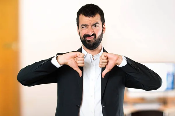 Hombre de negocios guapo haciendo mala señal en la oficina — Foto de Stock