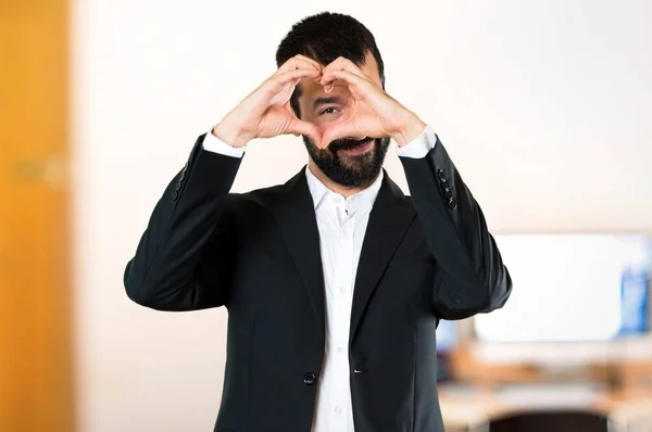 Schöner Geschäftsmann, der mit seinen Händen im Büro ein Herz macht — Stockfoto